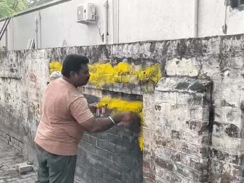 नारे लिखी गई जगह पर पेंट किया जा रहा है।